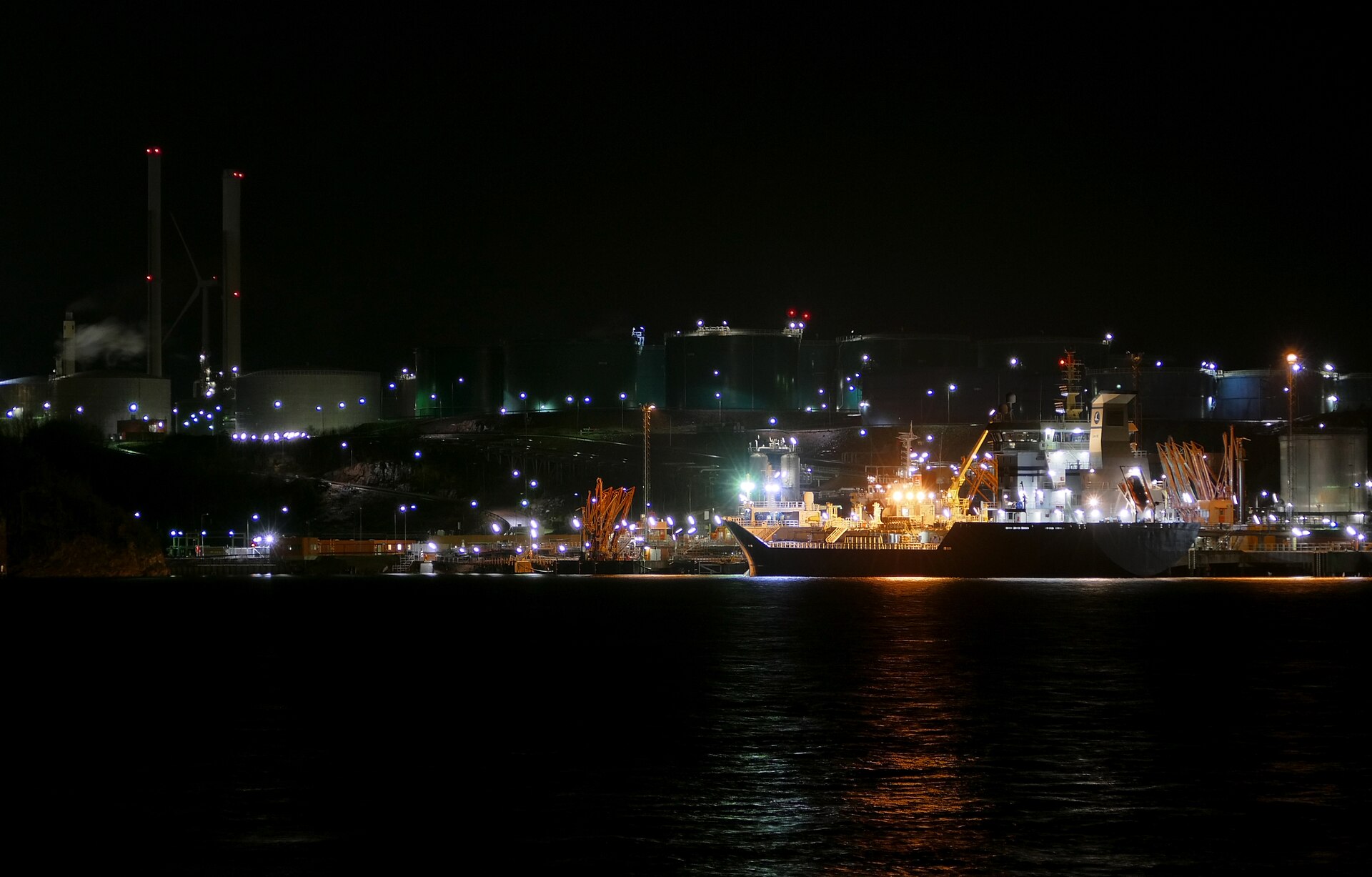 Product tanker alongside a refinery terminal at night